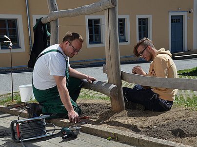 Schüler und ein Mann bauen einen Zaun